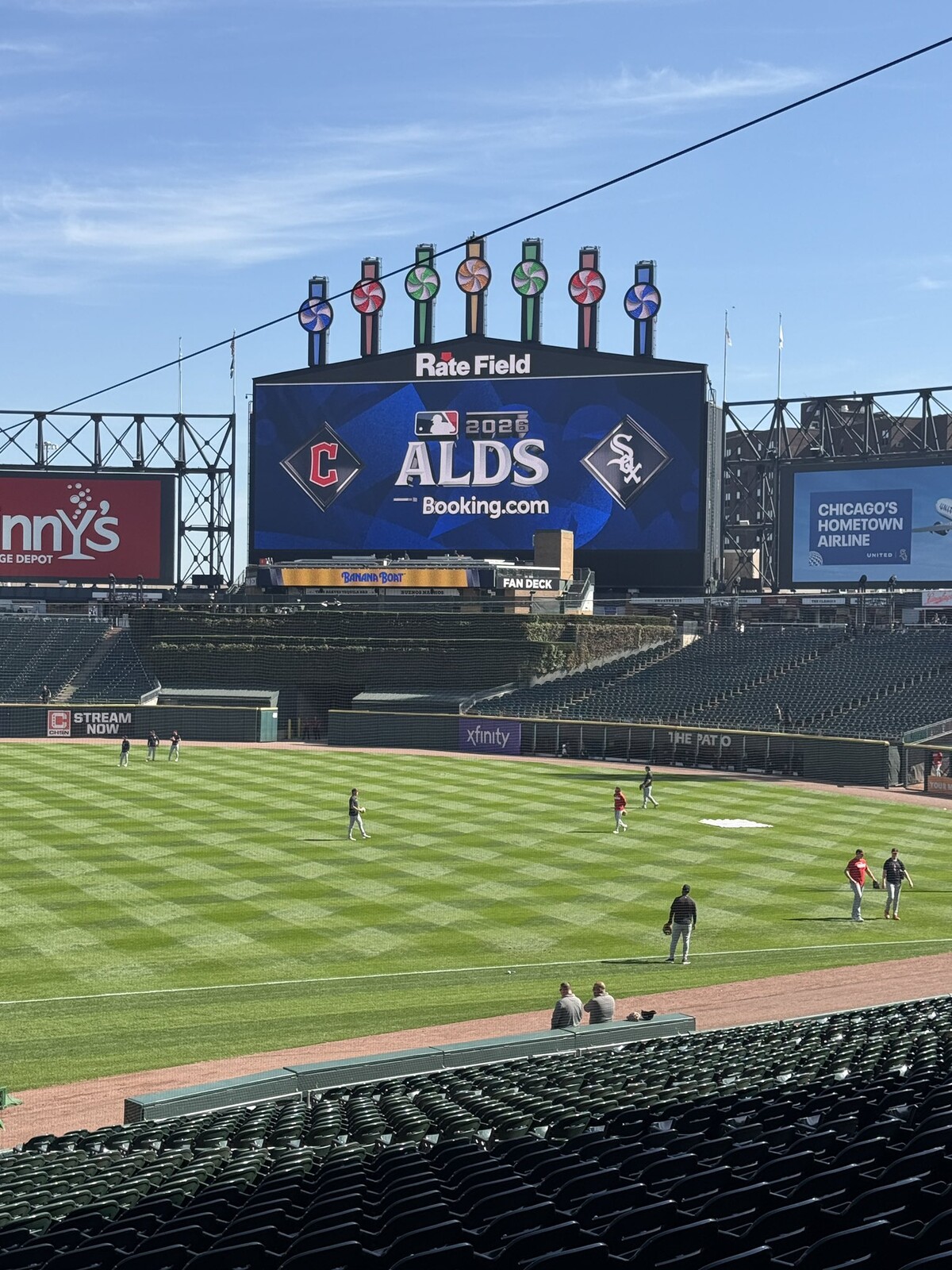 The Rate Field scoreboard displays the 2026 ALDS matchup between the Cleveland Guardians and Chicago White Sox while players warm up on the field