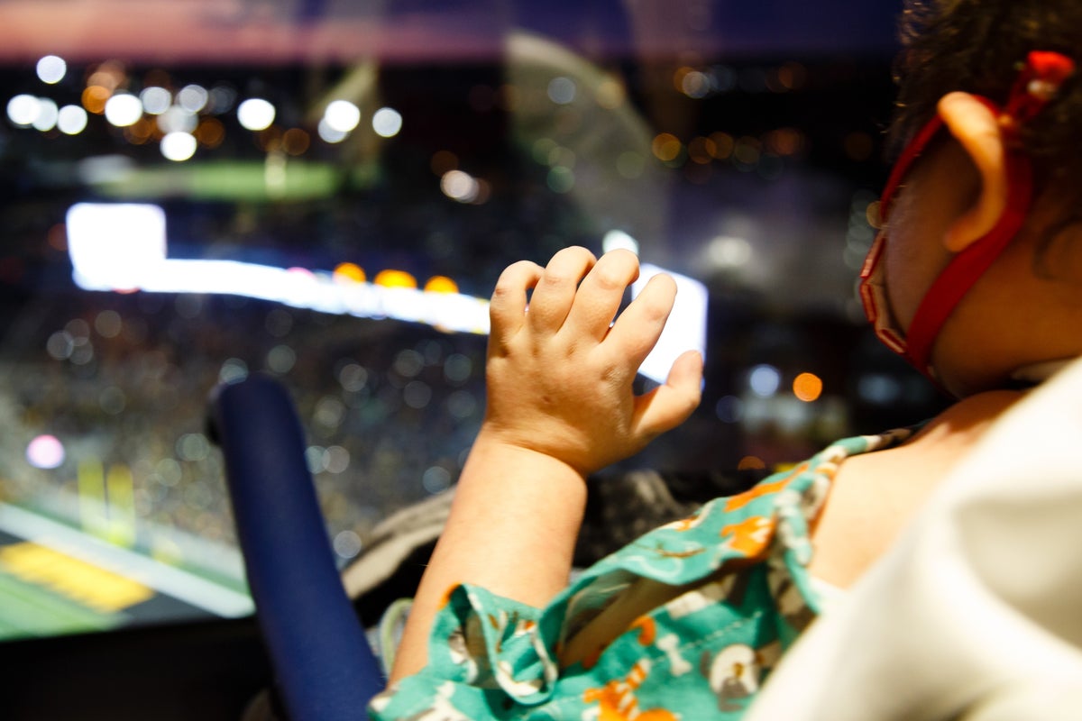 A child at University of Iowa Stead Family Children’s Hospital waves toward Kinnick Stadium during a night game in 2017