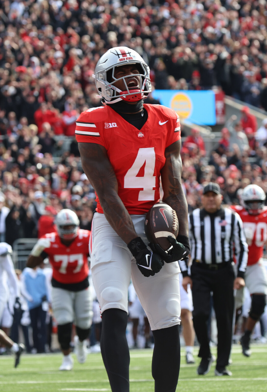 Ohio State receiver Jeremiah Smith, number 4, holding a football in his scarlet Buckeyes uniform