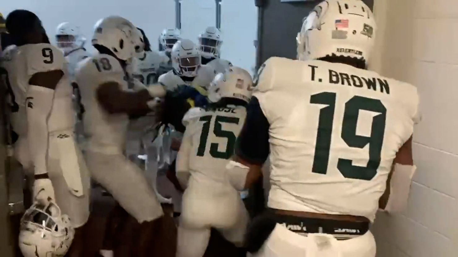 Michigan State players surrounding a Michigan player during a postgame confrontation in the stadium tunnel