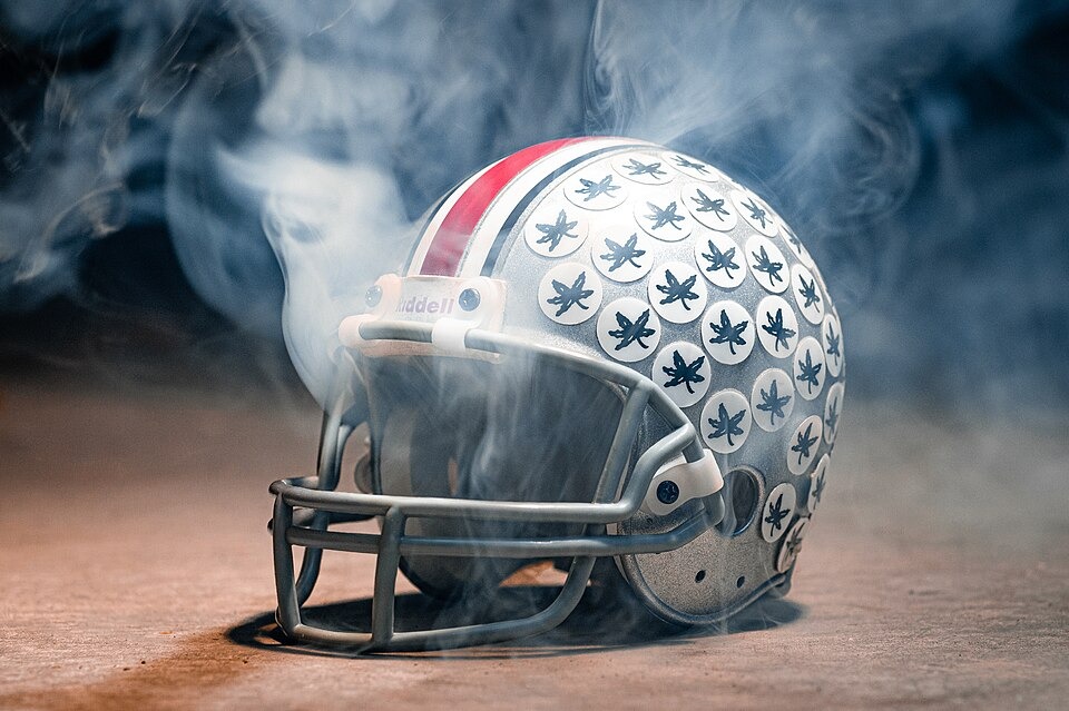An Ohio State football helmet covered in Buckeye leaf stickers, surrounded by mist